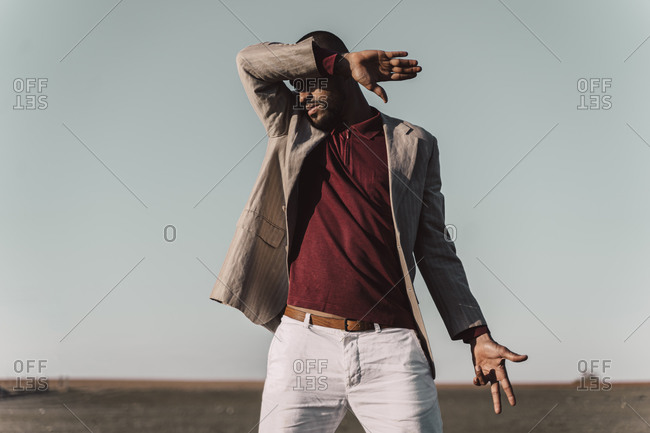 Young man standing in barren land shielding eyes