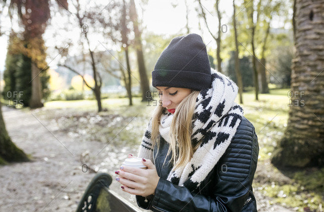 Beautiful blond woman having a take away coffee in a park