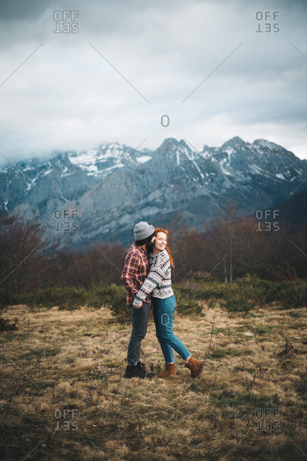 Side view of tender couple hugging and bonding with closed eyes in cold day in mountains