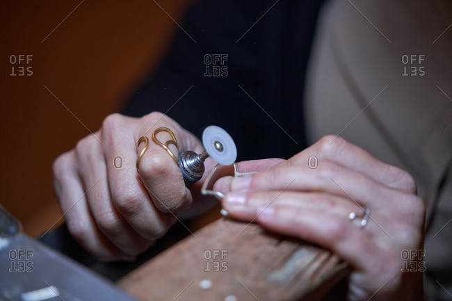 Cropped unrecognizable jeweler woman working in a jewelry shop, hands detail with jewelry and tools