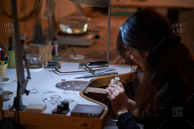 Beautiful artisan jeweler woman with working in a jewelry shop, hands detail with jewelry and tools