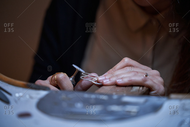 Cropped unrecognizable jeweler woman working in a jewelry shop, hands detail with jewelry and tools