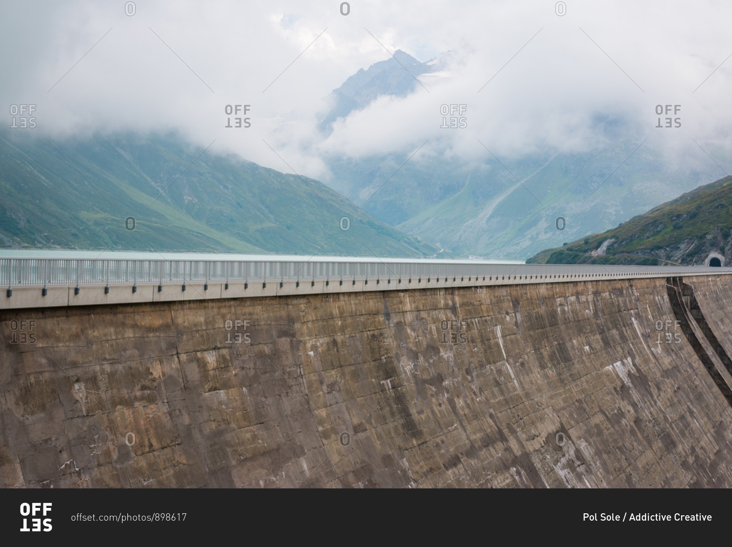 High alpine road on big dam on background with misty cloudy mountains in Austria