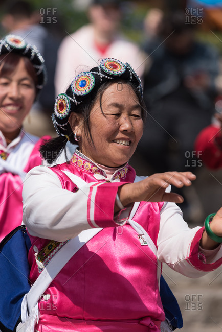 March 16, 2019: Laughing woman dancing in traditional costume of the Naxi ethnic group. Lijiang, China
