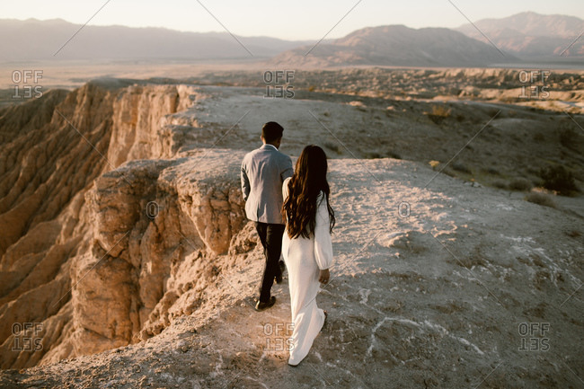 Rear view of couple holding hands and walking along a cliff together