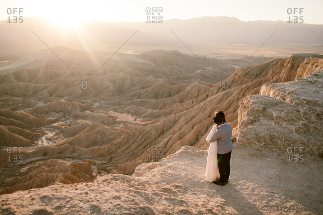 Man and woman holding each other while watching sunset at a desert overlook