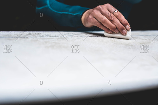 Close up of surfer's hand waxing board