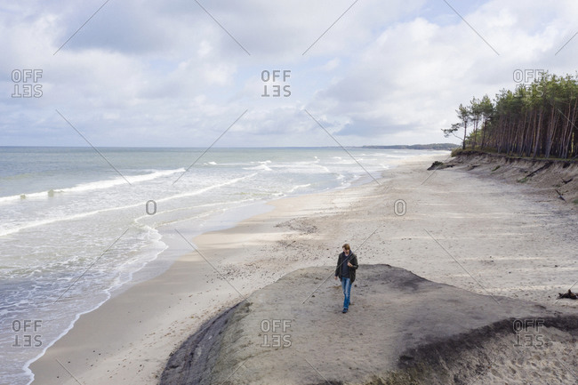 Russia- Kaliningrad Oblast- Zelenogradsk- Man walking along sandy coastal beach of Baltic Sea