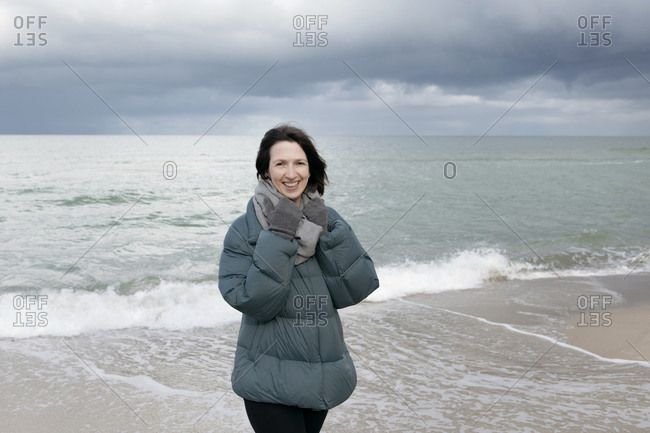 Russia- Kaliningrad Oblast- Zelenogradsk- Portrait of young woman standing on coastal beach and smiling at camera