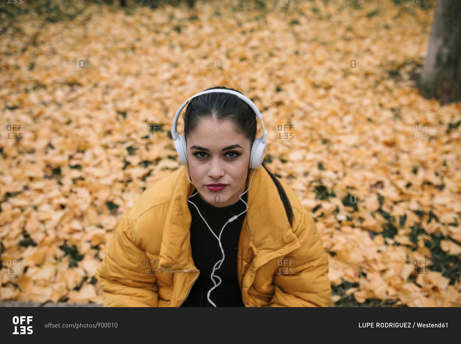Portrait of young woman listening music with headphones in autumn