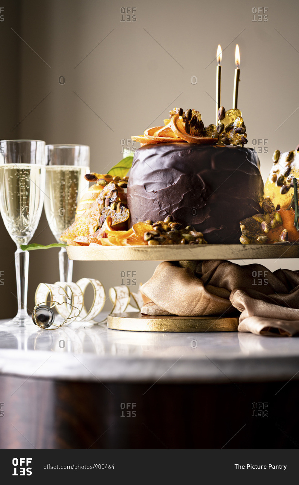 An Epic Gluten-free Chocolate Cake with ricotta cheese filling, chocolate frosting, chocolate glaze, orange slices and pistachio praline served with champagne.
