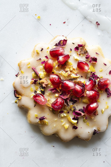 Gluten-free Sugar Cookies with eggless glaze decorated with pomegranate seeds, rose petals and pistachio