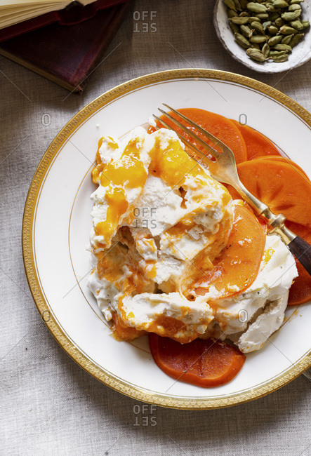 A multiple layered Pavlova Cake served with Fresh whipped cream  flavored with fresh ground cardamom, persimmons puree, persimmons slices.