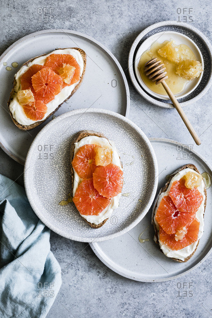 Honey orange ricotta toast on a ceramic plate. Vanilla-laced whipped ricotta gets swirled on toast and topped with orange slices and a drizzle of honey