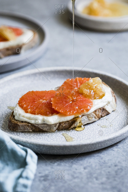 Honey orange ricotta toast on a ceramic plate. Vanilla-laced whipped ricotta gets swirled on toast and topped with orange slices and a drizzle of honey