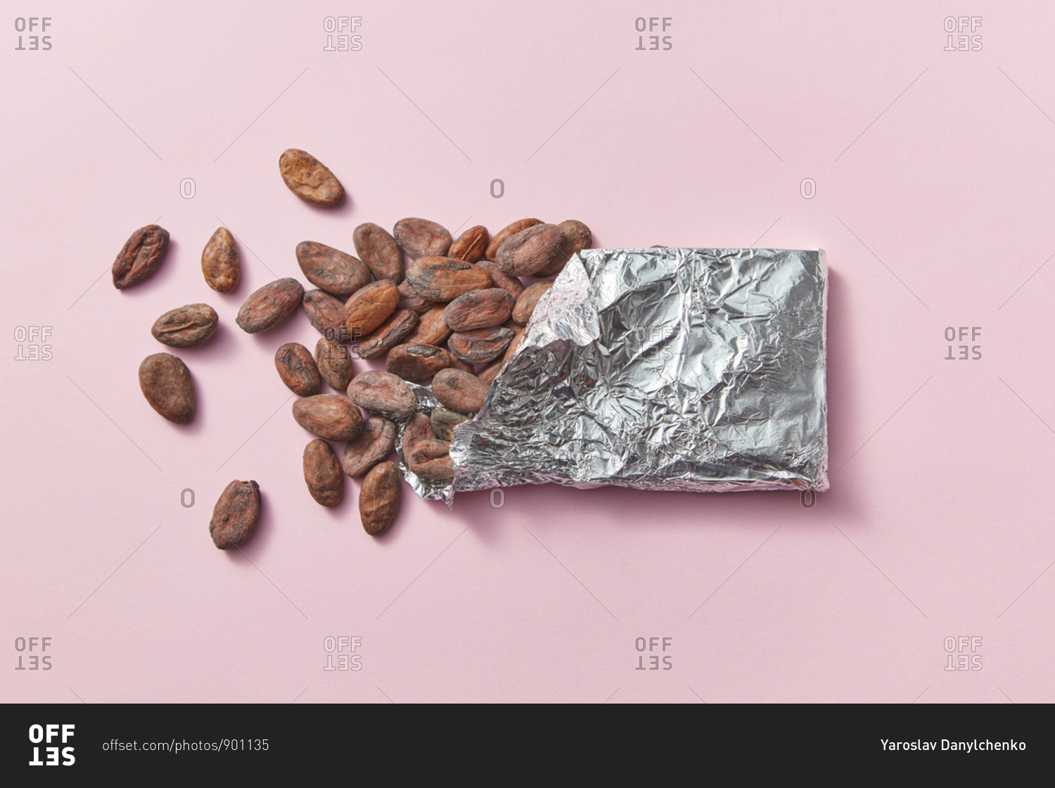Chocolate bar made up of natural organic cocoa beans in tin foil on a light pink background with copy space.