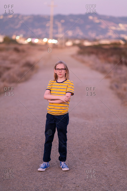 Tween standing on dirt road looking at camera at twilight