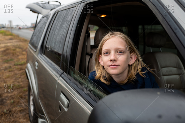 Tween looking at camera from passenger seat of suv