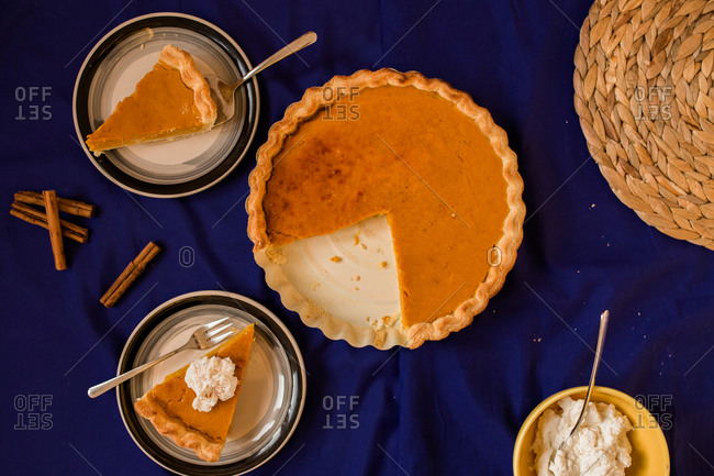 Top view of pumpkin pie and slice served on a plate with whipped cream