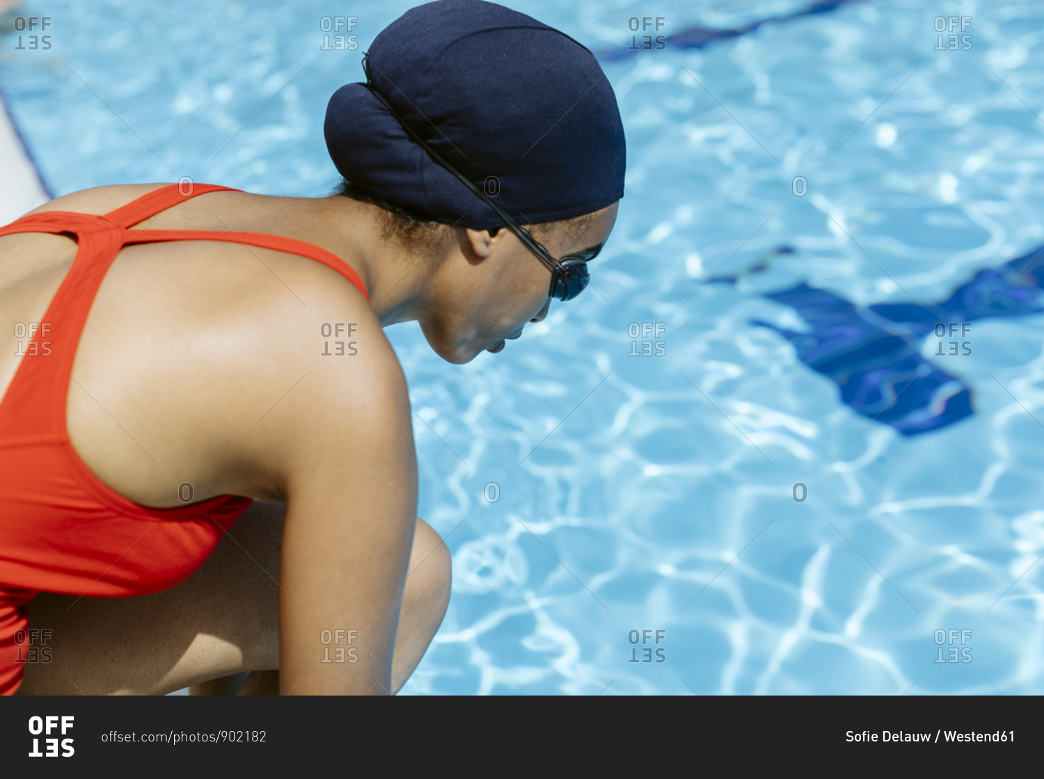 Young woman wearing swimming cap and goggles at poolside