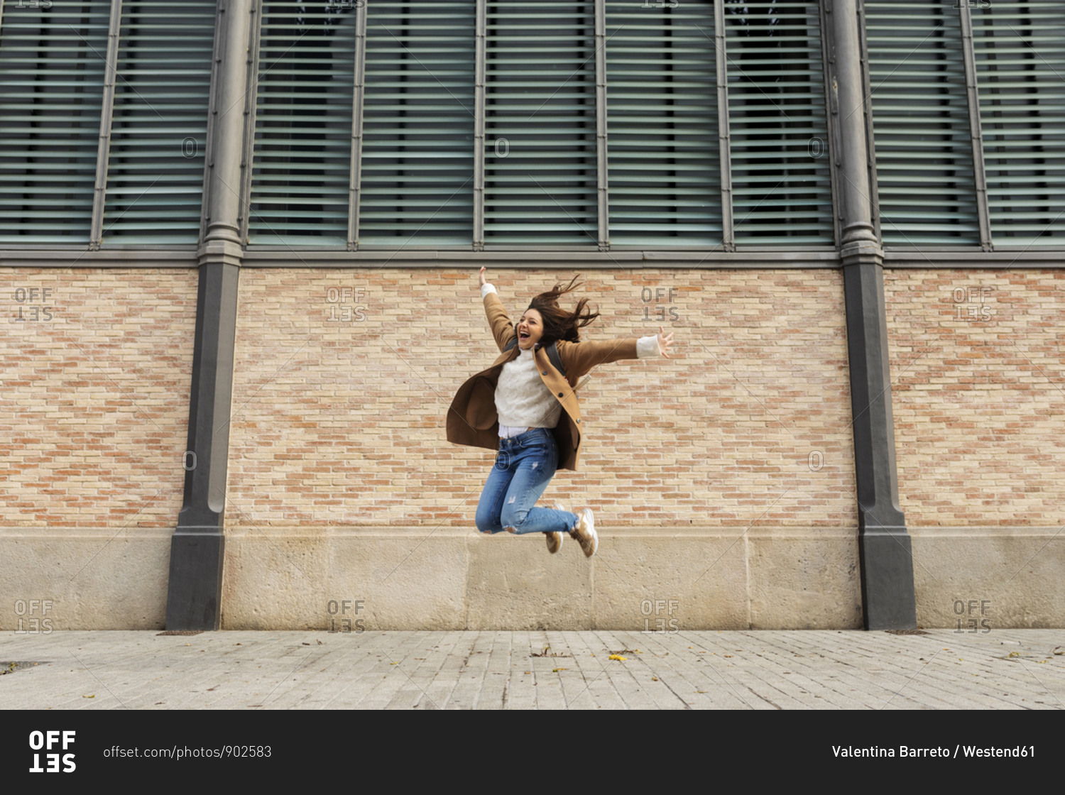 Excited young woman jumping in the city