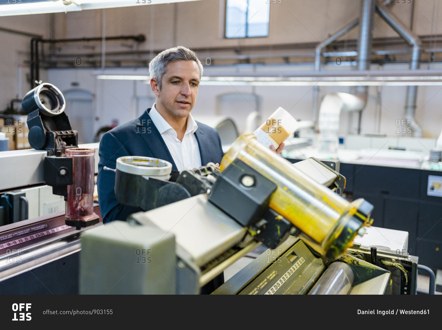 Businessman in a factory looking at a machine