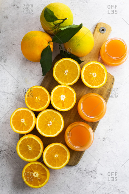 Freshly cut oranges and jars of orange juice on cutting board