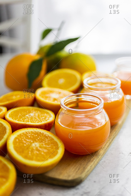Freshly cut oranges and jars of orange juice on cutting board