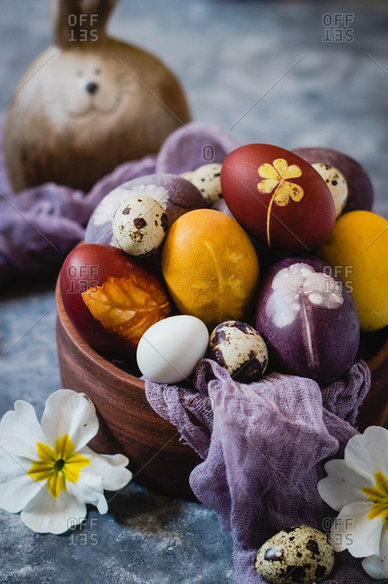 Naturally dyed Easter eggs on wooden bowl, front view