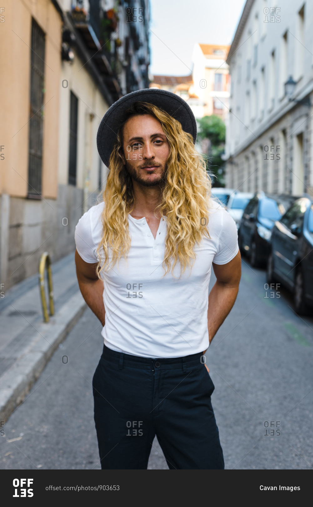 Handsome trendy long blonde haired guy looking at camera with a hat