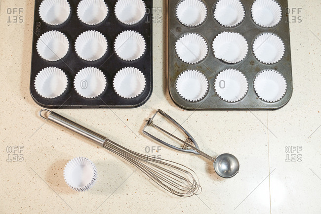 Stock photo of oven silver with baking holes together with baking papers, a hand mixer and a portioned Ice cream scoops