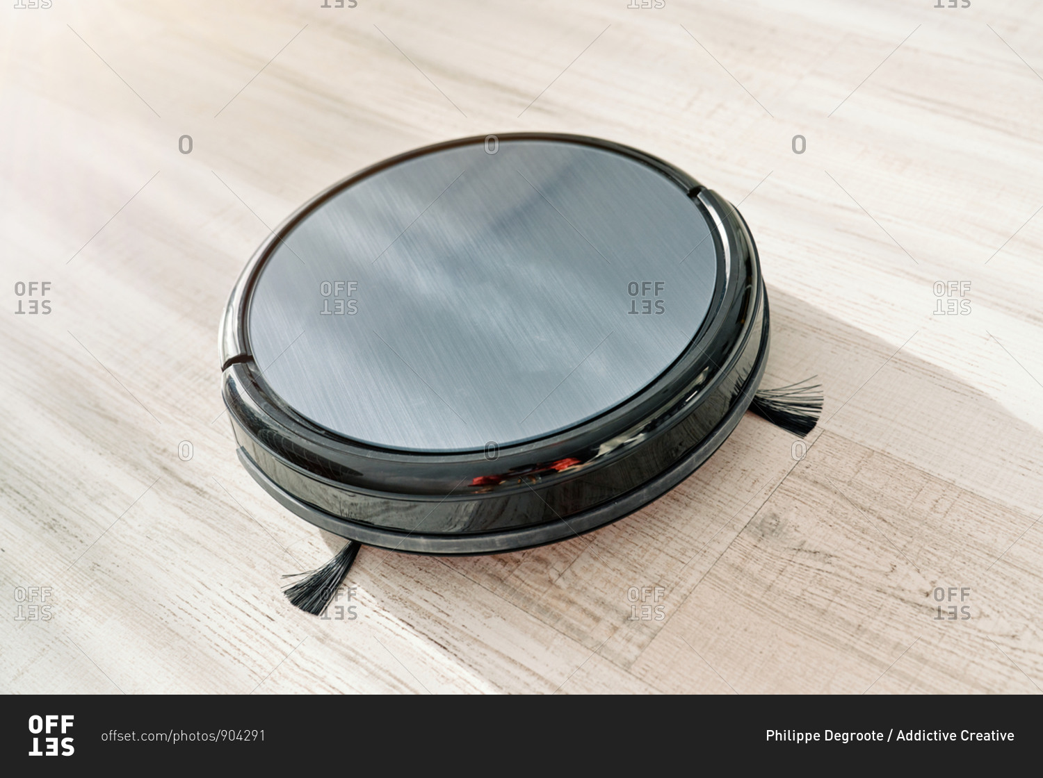 From above of round robotic vacuum cleaner sliding on light laminate floor