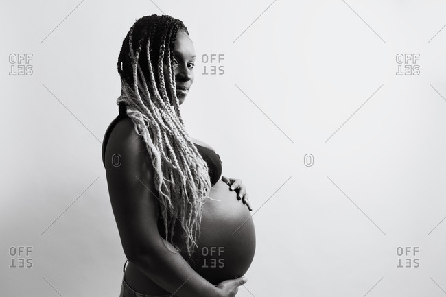 Caucasian pregnant woman with dreadlocks in boho style. White mehendi on  big belly. Expectation of baby in new age lifestyle. Stock Photo