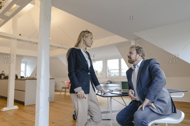 Businessman and businesswoman talking at table tennis table in office