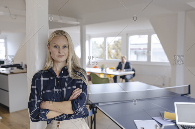 Portrait of young businesswoman in office with table tennis table