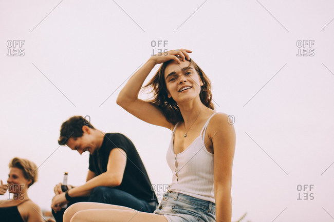 Portrait of smiling young woman enjoying party with friends on terrace during windy day
