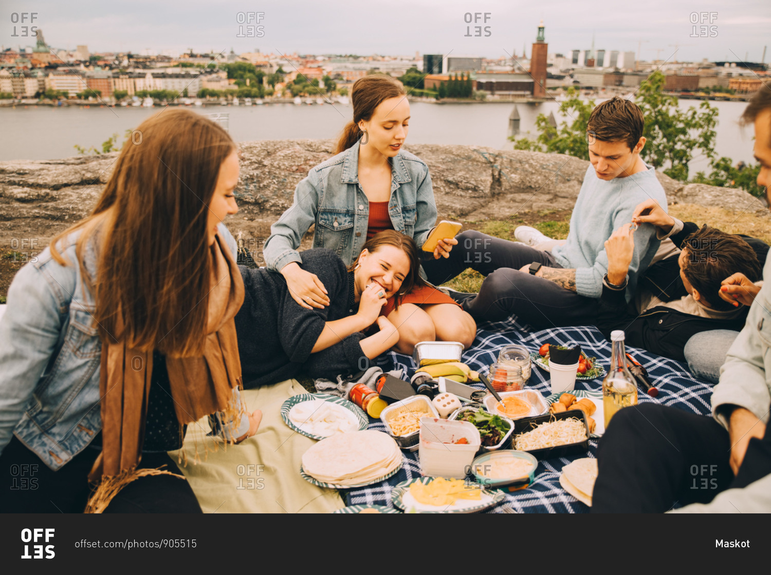 Male and female friends enjoying food on picnic blanket