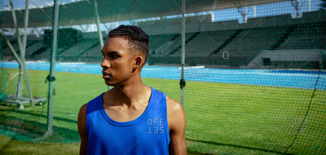 Side view of a mixed race male athlete practicing at a sports stadium, looking away from the camera. Track and Field Sports Training in Stadium.