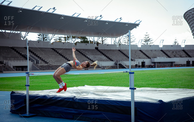 Side view of a Caucasian female athlete practicing at a sports stadium, doing a high jump. Track and Field Sports Training in Stadium.