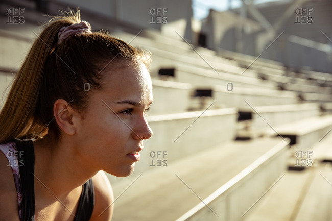 Side view close up of a Caucasian female athlete practicing at a sports stadium, focusing before a race. Track and Field Sports Training in Stadium.