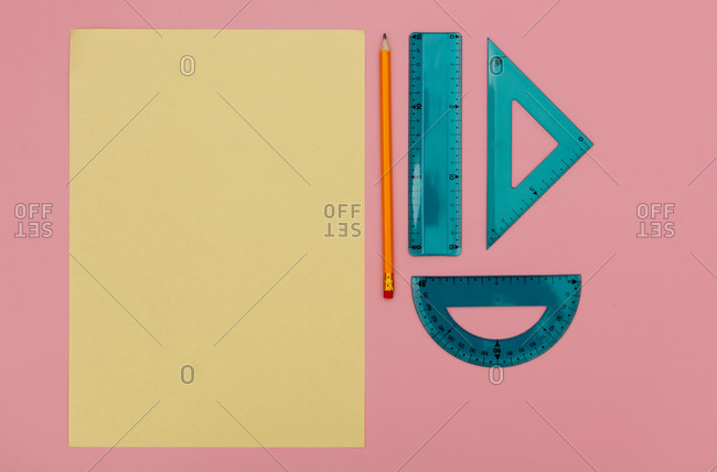 Paper and pencil with school supplies on pink background