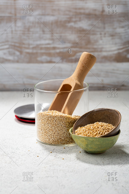 Quinoa in storage jar and small bowls with a wooden scoop