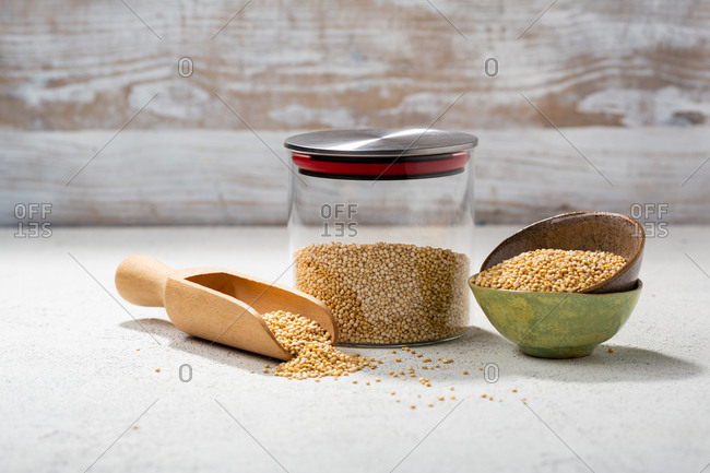 Quinoa in a glass jar beside small bowls with a wooden scoop