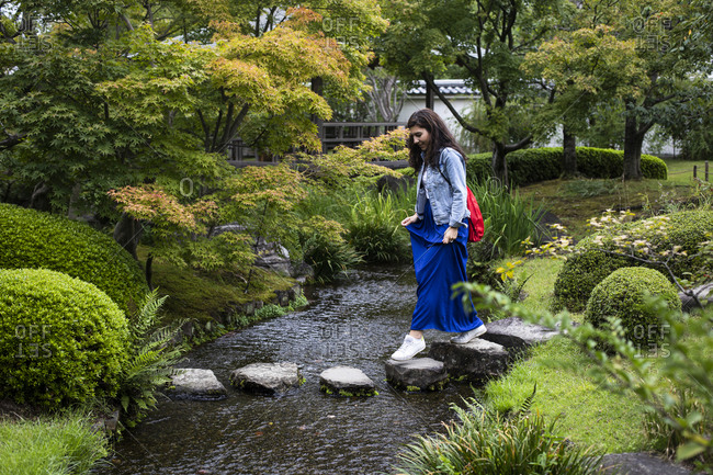 Japan- Kyoto- Woman on stepping stones in pond