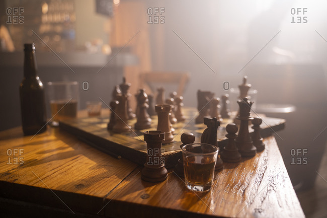 Old wooden chess board and drink on table in a pub