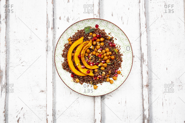 Studio shot of salad of red quinoa with baked pumpkin- chickpeas- pomegranate- basil- walnuts and pumpkin seeds