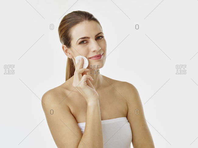 Portrait of smiling woman cleaning face with cotton pad
