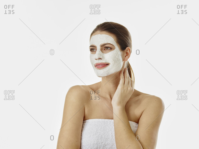 Portrait of smiling woman with beauty mask in front of white background