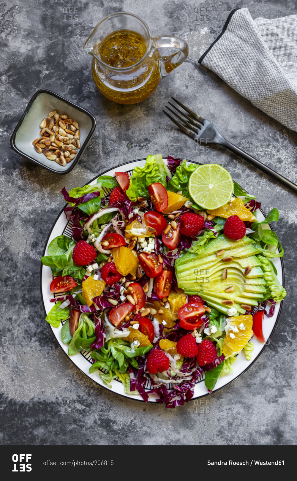 Studio shot of fruity salad plate with lambs lettuce- radicchio- lettuce hearts- avocado- tomato- pine nuts- raspberries- oranges- lime