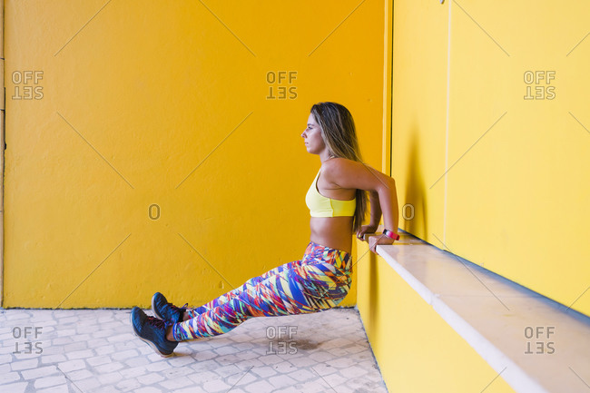 Woman doing wall sit by yellow wall